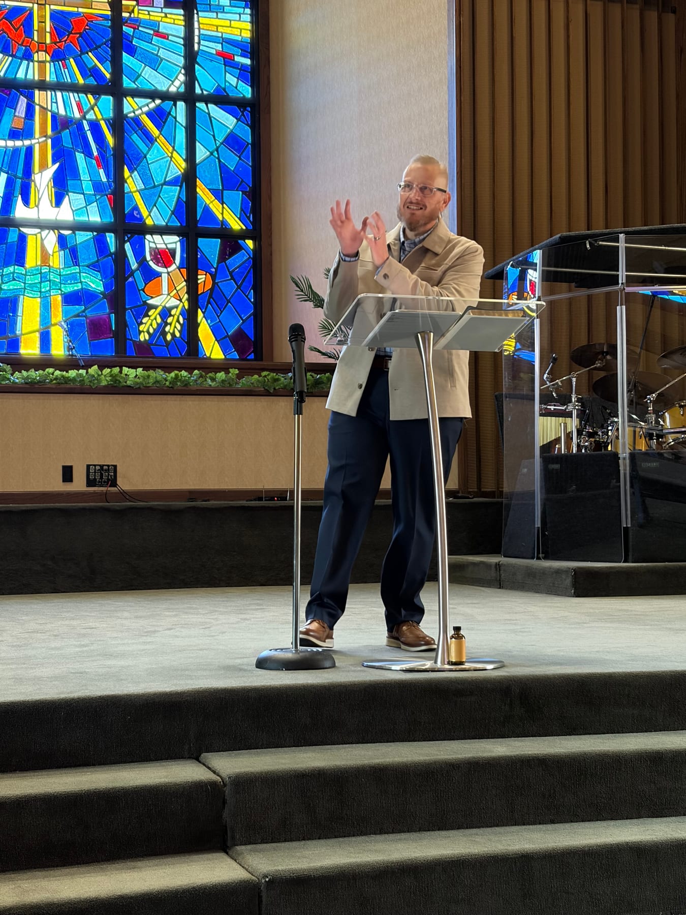 Pastor David Crawford preaching at GT Church beside the stained-glass window